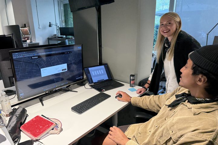 Erika and Elias at a desk, a city map interface open on the monitor in front of them.